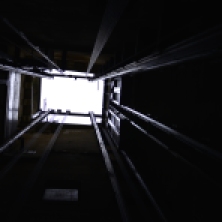 Looking up inside an open lift, itself inside a roofless bell-tower in Sarlat